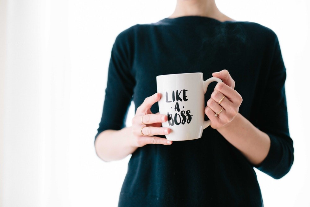 Photo of woman's torso with hands holding a mug that reads 'Like a Boss'