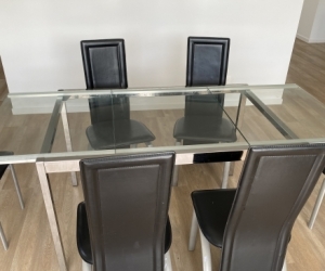 extendable glass top dining table and six black chairs